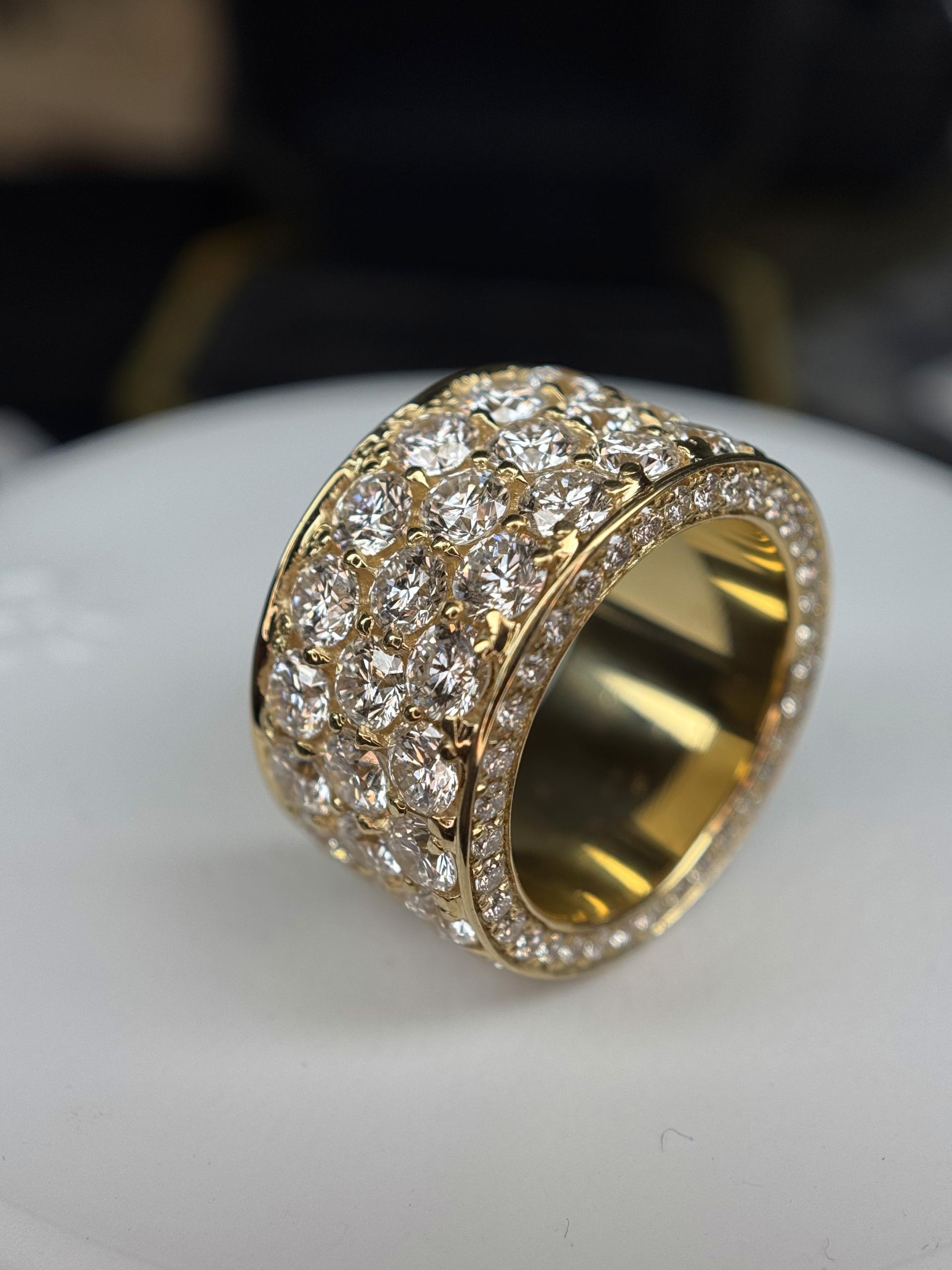A wide gold band set with multiple rows of pavé diamonds