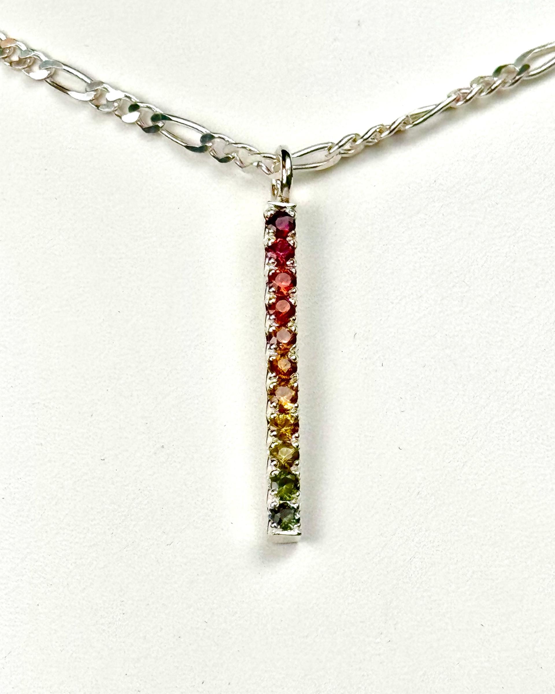Silver bar with rainbow natural sapphires set in a gradient from red to green using fishtail pave.
